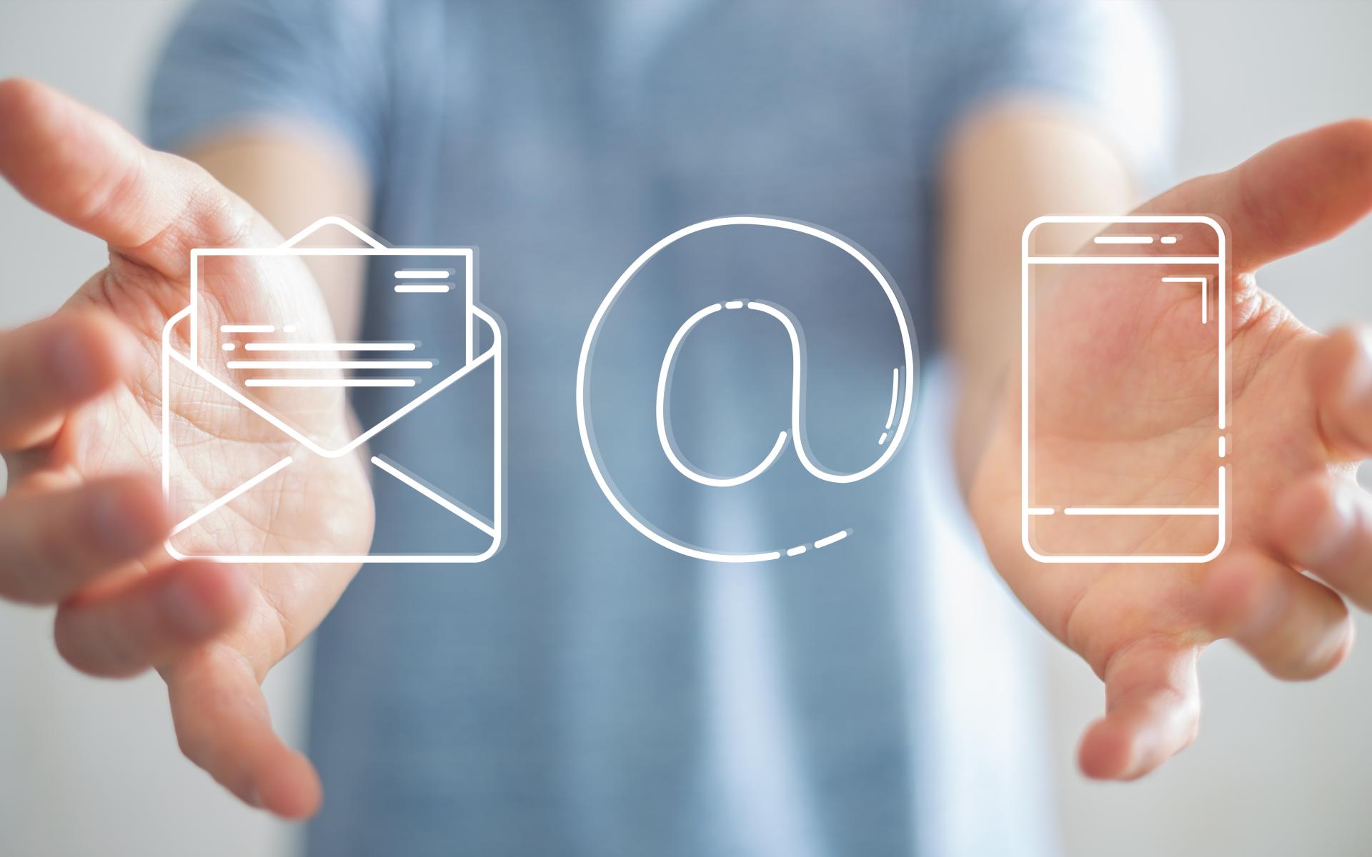 Hände halten Symbole: Briefkuvert, @-Zeichen und Smartphone